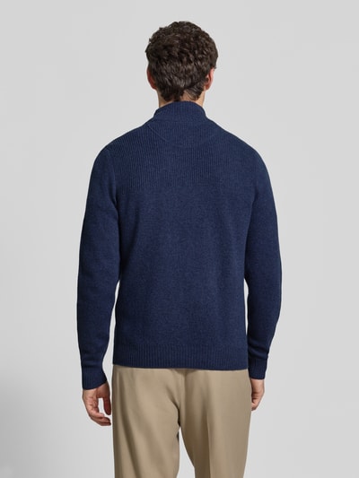 Männermodel trägt Regular Fit Strickpullover aus reiner Wolle von MCNEAL in Dunkelblau, Troyer-Kragen, gerippte Bündchen, Ganzkörperansicht Rückansicht.