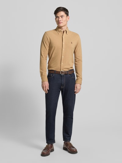 Männermodel trägt Freizeithemd mit Knopfleiste von Polo Ralph Lauren aus reiner Baumwolle im Regular-Fit, Button-Down-Kragen, Label-Stitching, beige, kombiniert mit dunkelblauer Hose, Ganzkörperansicht von vorne.