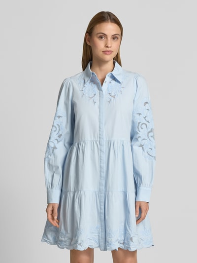Frauenmodel trägt knielanges Hemdblusenkleid mit Lochstickerei Modell 'Zimia' von YAS, Reine Baumwolle, Taillierte Passform, Langärmelig, Umlegekragen, durchgängige Knopfleiste, Rückenlänge bei Größe 36: 92 cm, Brustweite 51 cm, Ärmellänge 67 cm, hellblaue Farbe, florale Muster, geschwungene Säume, glatte Textur, Ganzkörperansicht von vorne.