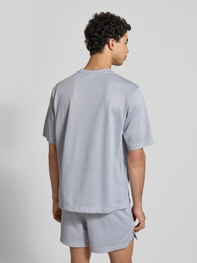 Männermodel trägt T-Shirt mit Label-Print von adidas Training in Grau, Regular-Fit, aus glattem Stoff mit Rundhalsausschnitt, Rückenlänge 70 cm bei Größe M, Ganzkörperansicht Rückansicht.
