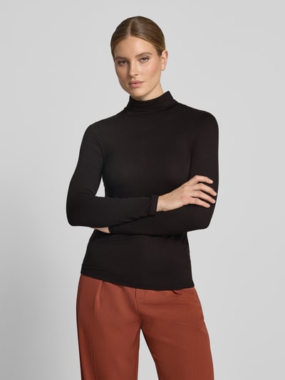 Vrouwenmodel draagt zwarte shirt met lange mouwen met col van Christian Berg Woman, viscosemix, recht model, ruglengte bij maat S 60 cm, frontale borstbeeldopname.