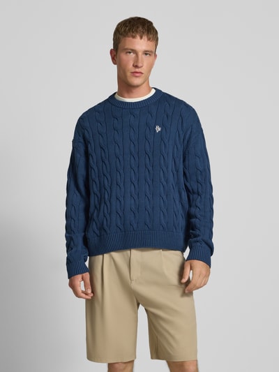 Männermodel trägt Strickpullover mit Zopfmuster und Label-Stitching von REVIEW, reine Baumwolle, regular fit, Rundhalsausschnitt, Ganzkörperansicht von vorne