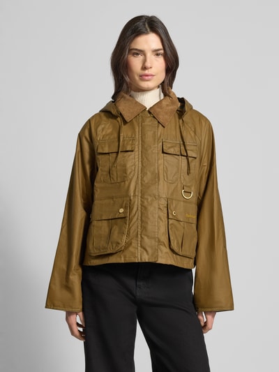 Modelka kobieca nosi Regular Fit Funktionsjacke aus reiner Baumwolle Modell 'LIZA' od Barbour, jednokolorowa, bawełna, krój regular fit, odpinany kaptur, zapięcie na napy i zamek, metaliczne akcenty, naszywane kieszenie, długi rękaw, detal z logo, widok całej sylwetki z przodu.