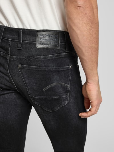Mężczyzna model nosi Skinny Fit Jeans mit 5-Pocket-Design od G-Star Raw, czarny bawełniany dżins, detal tylnej kieszeni, zbliżenie tyłu.