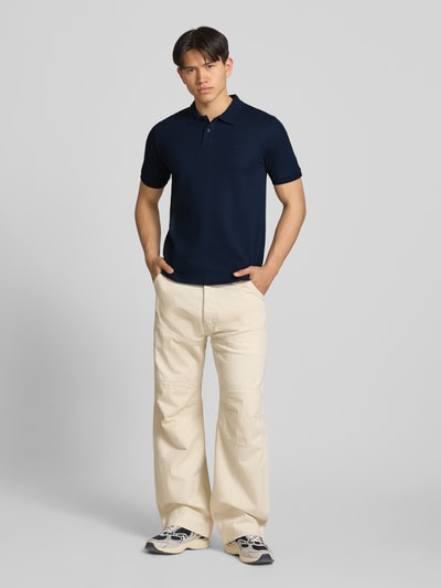 Männermodel trägt Regular Fit Poloshirt mit Strukturmuster Modell 'AUSTIN' von Jack & Jones in Dunkelblau, Material-Mix; Ganzkörperansicht von vorne.