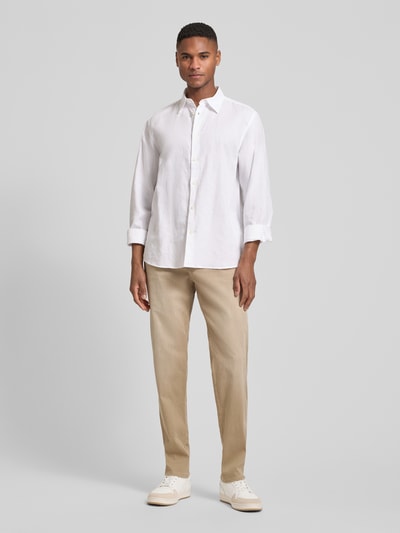 Männermodel trägt Regular Fit Jeans mit Eingrifftaschen von bugatti aus Baumwoll-Mix mit Stretch-Anteil in Beige, Ganzkörperansicht von vorne.