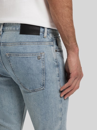 Männermodel trägt Slim Fit Jeans aus katoenmix Modell 'DELAWARE BO' van BOSS Orange in denimlook met logo-applicatie, detailaufnahme achterzijde