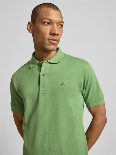 Männermodel trägt Regular Fit Poloshirt aus reiner Baumwolle von Lacoste in Grün mit Polokragen, Logo-Stitching, Nahaufnahme Oberkörper