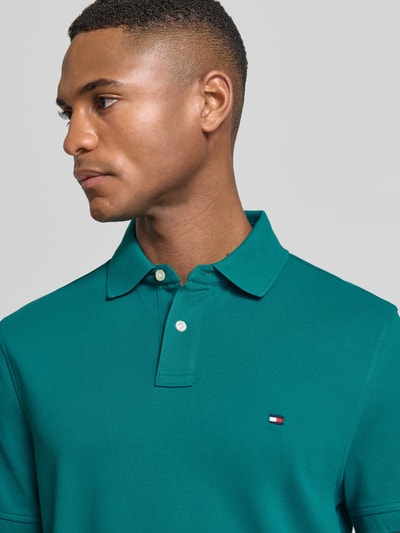 Männermodel trägt Regular Fit Poloshirt aus bawełny-mix von Tommy Hilfiger, efekt: jednolity kolor, wyhaftowane logo, kołnierzyk polo, zapięcie na 2 guziki, krótki rękaw, pika, mieszanka bawełny, nahaufnahme górnej części ciała.
