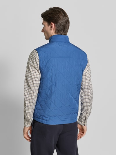Männermodel trägt Regular Fit Weste mit Stehkragen in Stepp-Optik von Gant in Blau mit Logo-Stitching und Reißverschluss, Ganzkörperansicht Rückansicht. Rückenlänge bei Größe M: 69 cm, Schulterbreite: 45 cm, Brustweite: 57 cm.