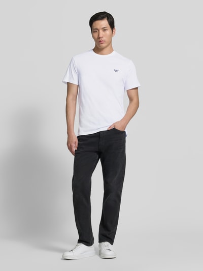 Männermodel trägt T-Shirt mit Logo-Patch und Rundhalsausschnitt von Emporio Armani, Reine Baumwolle, Modern Fit, Rückenlänge 69 cm, Ganzkörperansicht von vorne.