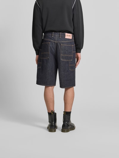 Männermodel trägt Straight Fit Shorts in Denim-Optik von Kenzo aus reiner Baumwolle mit Cargo-Taschen, Knopf-Reißverschluss, Ganzkörperansicht Rückansicht.