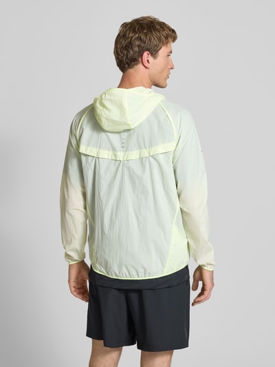 Männermodel trägt Trainingsjacke mit Logo-Print und Kapuze von NIKE TRAINING in hellem Gelb, glatte Textur, Rückansicht, Ganzkörperansicht. Gerader Schnitt, Reißverschluss, Kapuze, Rückenlänge 71 cm, Ärmellänge 66 cm.