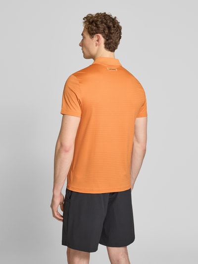 Männermodel trägt Lacoste Slim Fit Poloshirt aus schnelltrocknendem Material, Optik: Unifarben, Logo-Patch, Ganzkörperansicht Rückansicht.