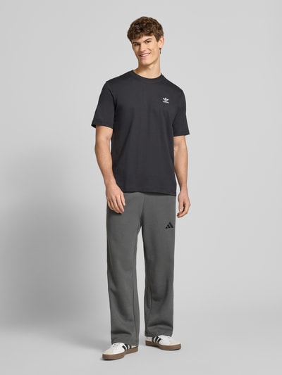 Männermodel trägt Sweatpants mit elastischem Bund und Tunnelzug von adidas Sportswear, grau, Regular Fit, Logo, Ganzkörperansicht von vorne.