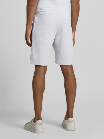 Männermodel trägt Regular Fit Shorts mit Tunnelzug von MCNEAL, helles Baumwoll-Mix Material, sichtbare Gesäßtasche, Ganzkörperansicht Rückansicht.
