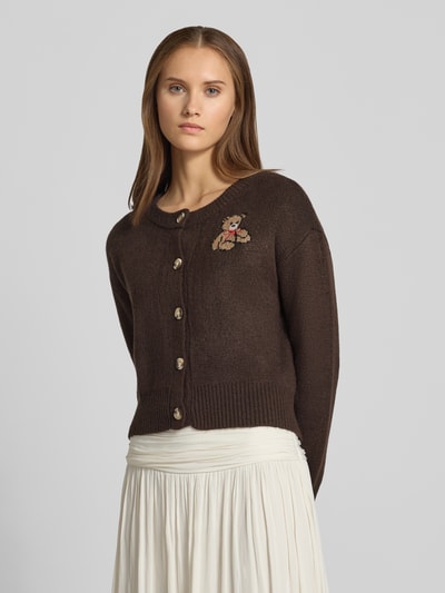 Frauenmodel trägt Relaxed Fit Strickpullover mit Stickerei Modell 'TEDDY' von ONLY, dunkelbraun, cremefarbener Rock, Ganzkörperansicht von vorne, Damen Strickjacke von ONLY.