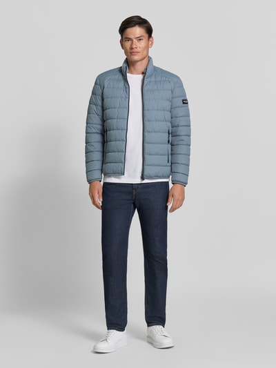 Männermodel trägt Regular Fit Steppjacke mit Zweiwege-Reißverschluss von Marc O'Polo in Blau, glatte Struktur, Ganzkörperansicht von vorne. Herren Steppjacke von Marc O'Polo