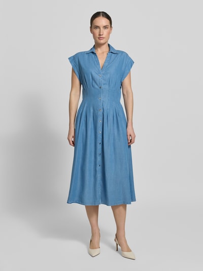 Frauenmodel trägt mittelblaues Hemdkleid aus Denim, weich fallender Stoff, Knopfleiste, A-Linie, Ganzkörperansicht von vorne.