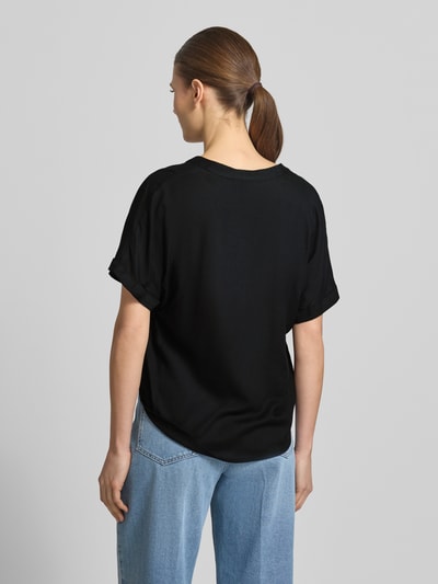 Männermodel trägt Relaxed Fit Blusenshirt aus reiner wiskoza Modell 'BEAUTY' von Vero Moda, efekt: jednolity kolor, krój relaxed fit, tunika, dekolt w serek, krótki rękaw, zakończenia rękawów: stały brzeg, wykończenie: zaokrąglony, materiał: czysta wiskoza, Ganzkörperansicht Rückansicht.