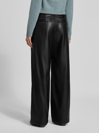Frauenmodel trägt Relaxed Fit Weite Hose mit Bundfalten Modell 'TADESA' von BOSS, Glänzend-Optik, Kunstleder, High-Waist, Ganzkörperansicht Rückansicht.