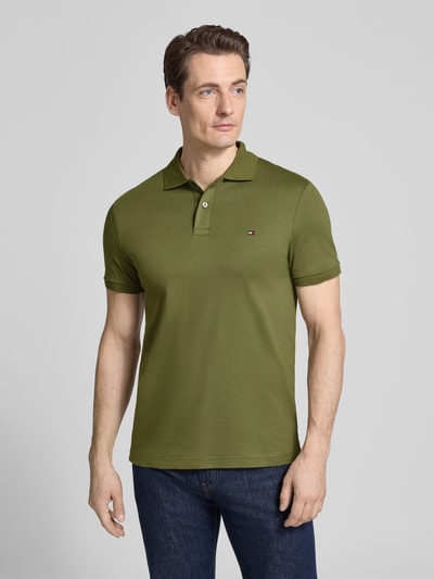 Männermodel trägt Regular fit Poloshirt aus puur katoen Model 'LIQUID COTTON' von Tommy Hilfiger in mêlee met logostitching, polokraag, korte mouw, mouwboord, rompzoom met zijsplitten, melangelook, Ganzkörperansicht von vorne.