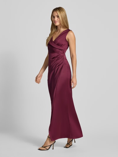 Frauenmodel trägt Abendkleid mit Raffungen von Rinascimento aus bordeauxfarbenem Satin mit V-Ausschnitt, Ganzkörperansicht von vorne.