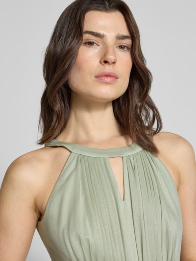 Frauenmodel trägt Regular Fit Abendkleid aus Glitzer-Mesh von Jake*s Cocktail in zartem Pastellgrün, Schlüssellochausschnitt, Falten-Optik, taillierte Passform, Nahaufnahme Oberkörper.