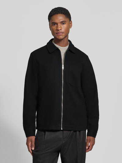 Männermodel trägt Jacke mit Brusttasche und Kentkragen Modell 'ROLFSTED' von Casual Friday in Schwarz, gerader Schnitt, Ganzkörperansicht von vorne.