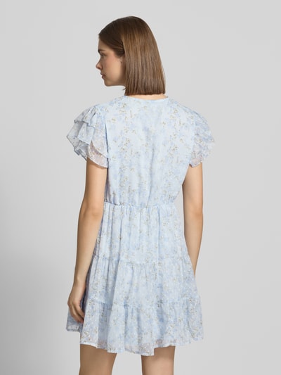 Frauenmodel trägt Tailliertes Freizeitkleid mit Volants Modell 'ELIZA' von Only mit florales Allover-Muster, Crinkle-Design, Mini-Länge, Rundhals; leichte, strukturierte Optik, überwiegend helle Blautöne, Ganzkörperansicht Rückansicht.