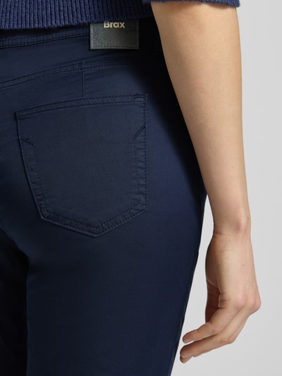 Frauenmodel trägt Hose in verkürzter Passform Modell 'Mary' von Brax aus dunkelblauem Baumwoll-Mix mit Lyocell, Nahaufnahme Rückansicht.