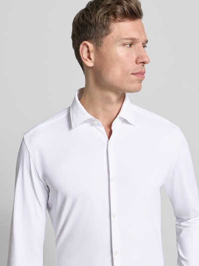 Männermodel trägt Slim Fit Business-Hemd Modell 'KENNO' von HUGO im Unifarbenes-Design, Material-Mix mit Stretch-Anteil, Nahaufnahme Oberkörper.