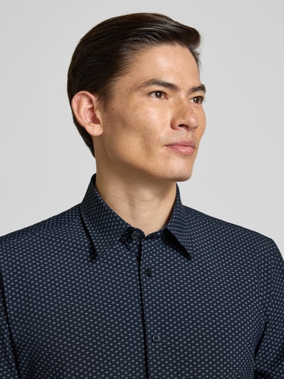 Männermodel trägt Regular Fit Businesshemd mit kurzem Arm Modell 'P-LIAM' von BOSS mit Allover-Muster, Nahaufnahme Oberkörper.