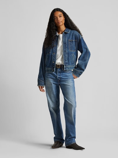 Frauenmodel trägt Relaxed Fit Jeansjacke aus reiner Baumwolle von Polo Ralph Lauren in Denim-Optik mit Umlegekragen und Knopfleiste, Ganzkörperansicht von vorne.