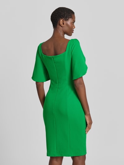 Frauenmodel trägt Cocktailkleid mit Karree-Ausschnitt von Adrianna Papell in leuchtendem Grün, figurbetont, kniefrei, Material-Mix mit Stretch, Ganzkörperansicht Rückansicht.