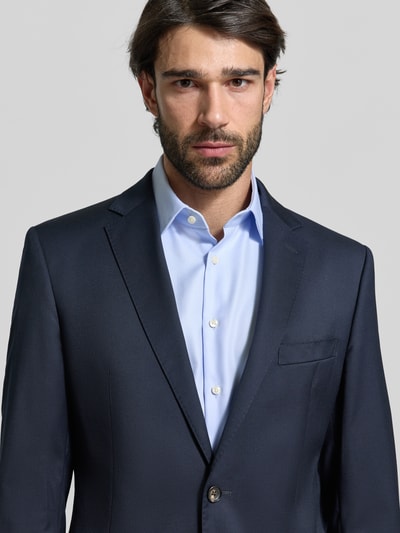 Männermodel trägt 2-Knopf-Sakko mit Reverskragen Modell 'Sono' von windsor. aus scheerwol-elastaanmix, uni design, recht model, borstzak, klepzakken, kleur donkerblauw, detailopname bovenlichaam.