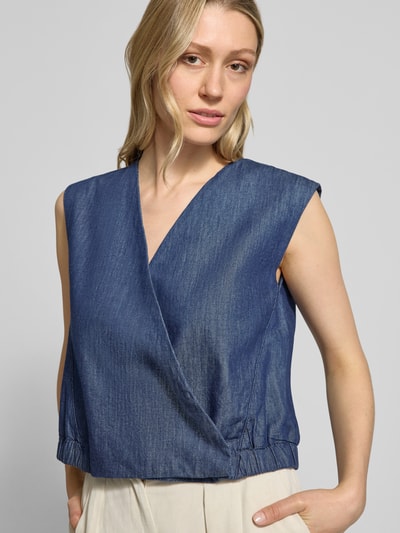 Frauenmodel trägt Weste mit V-Ausschnitt Modell 'Wiona' von OPUS aus reiner Baumwolle, Cropped, blaue Textur, Nahaufnahme Oberkörper. Rückenlänge 46 cm, Schulterbreite 41 cm, Brustweite 48 cm bei Größe 36.