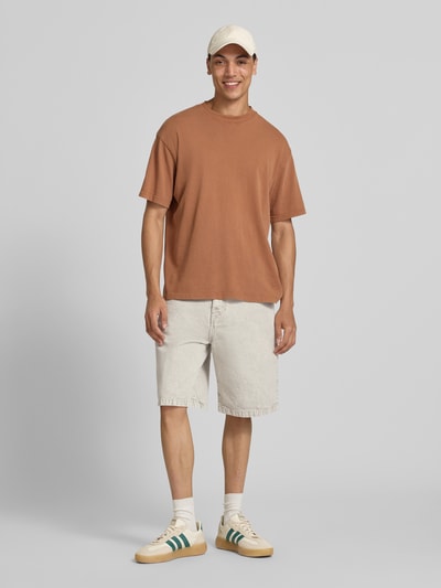 Männermodel trägt Jeansshorts mit Eingrifftaschen Modell 'Smithfield' von Carhartt Work In Progress in heller Farbe, Reine Baumwolle, Relaxed-Fit, Ganzkörperansicht von vorne.