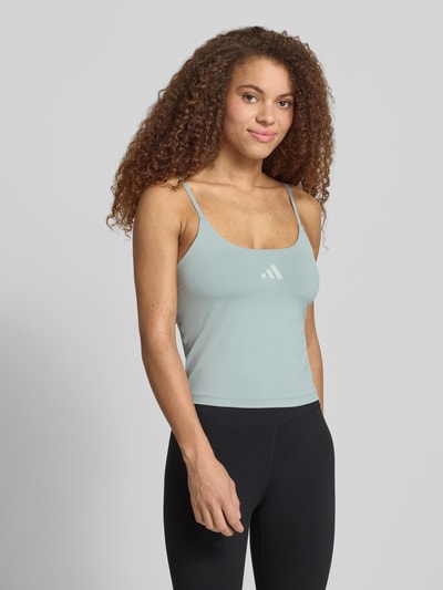 Frauenmodel trägt Slim Fit Sport Top mit Label-Print von adidas Sportswear in Optik: Unifarben, Stretch-Webstruktur, Nahaufnahme Oberkörper.