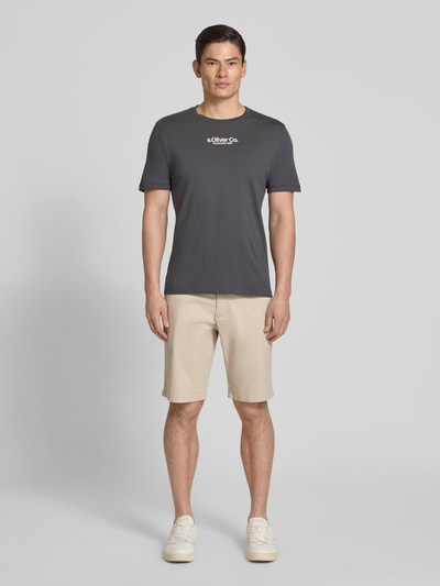 Mężczyznę model nosi Regular Fit Bermudas aus Baumwoll-Mix Modell 'PHOENIX' von s.Oliver RED LABEL, beżowy twill, widok całej sylwetki z przodu.