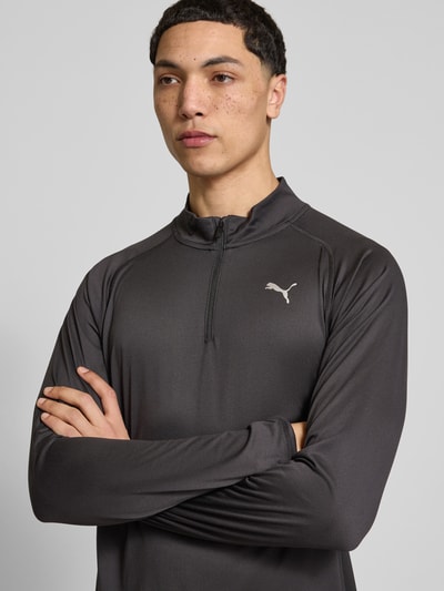 Männermodel trägt Langarmshirt mit Stehkragen und Reißverschluss von PUMA PERFORMANCE in Dunkelgrau mit Logo, Regular-Fit, Nahaufnahme Oberkörper. Rückenlänge bei Größe M: 71 cm.