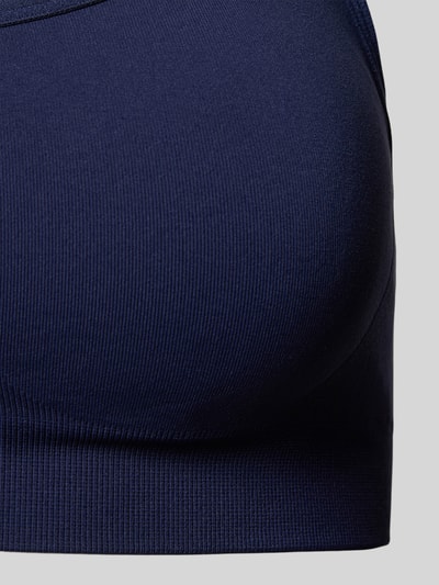 Männermodel trägt Slim Fit Sport-Bh mit verstellbaren Trägern von Fabletics, elastyczna mieszanka materiałów, krój slim fit, regulowane ramiączka, nadruk z logo, cienkie ramiączka, zbliżenie na górną część ciała