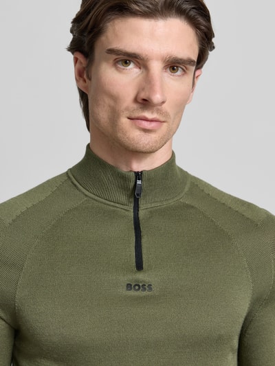 Männermodel trägt Regular Fit Troyer mit Schurwoll-Anteil Modell 'TOUR SEAMLESS QZ' von BOSS Green in Oliv, unifarben, Nahaufnahme Oberkörper.