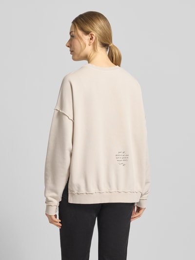 Modelka nosi Oversized Fit Sweatshirt mit Zier-Bordüren od Smith and Soul, bawełniana mieszanka, jasny beż, widoczne dekoracyjne przeszycia, widok całej sylwetki z tyłu