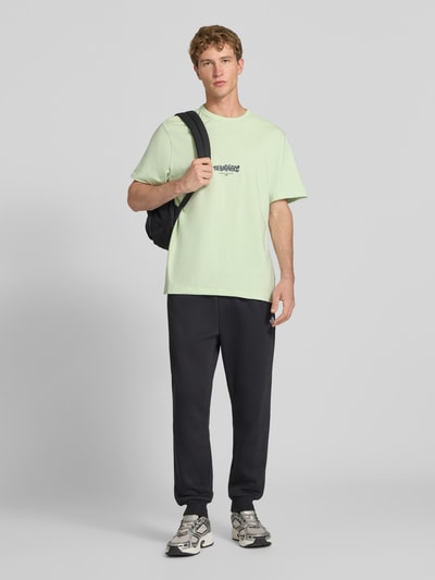 Mannenmodel draagt Relaxed Fit T-shirt uit puur katoen met logoprint van The North Face, kleur lichtgroen, ronde hals, ruglengte maat M 72 cm, voorkant volledige lichaamsweergave.