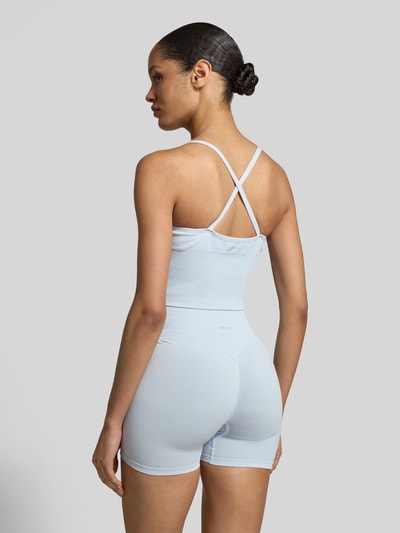 Frauenmodel trägt Crop Top mit überkreuzten Trägern von aim'n, hellblauer Material-Mix mit Stretch, Rückansicht, Ganzkörperansicht Rückansicht.