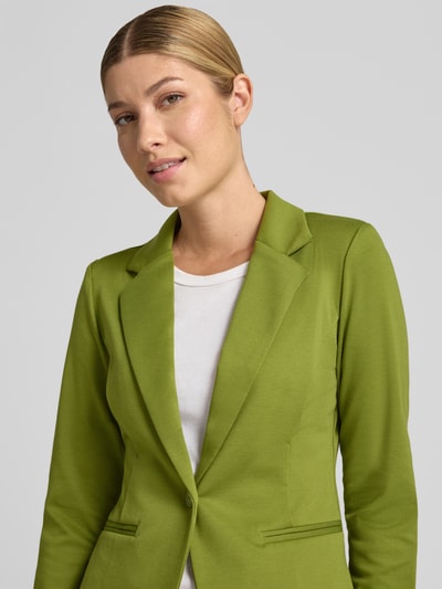 Frauenmodel trägt Blazer mit Viskose-Anteil Modell 'Kate' von ICHI, leuchtend grün, Reverskragen, tailliert, Nahaufnahme Oberkörper. Elastischer Material-Mix, Paspeltaschen, Rückenlänge 59 cm, Brustweite 45 cm, Ärmellänge 55 cm.
