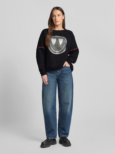 Modelka kobieca nosi czarne Sweatshirt mit Label-Detail od miss goodlife z bawełny, luźny krój, dżinsy, widok całej sylwetki z przodu.