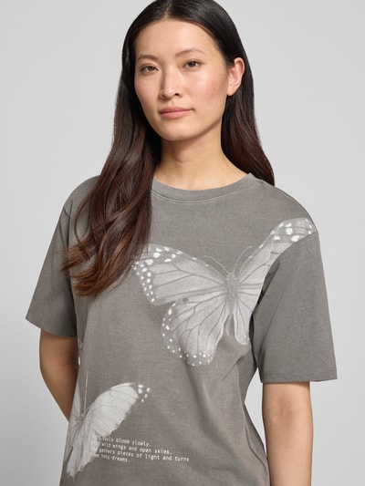 Frauenmodel trägt Relaxed Fit T-Shirt mit Motiv-Print von Jake*s Casual, Reine Baumwolle, Statement-Print, Rundhalsausschnitt, Rückenlänge bei Größe S 53 cm, Nahaufnahme Oberkörper.