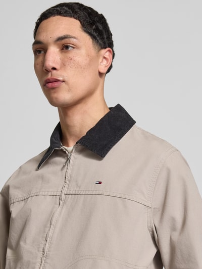 Męski model nosi Regular Fit Ranch-Jacke aus reiner Baumwolle von Tommy Jeans, jednokolorowa, wykładany kołnierz ze sztruksu, wyhaftowane logo, długi rękaw, zamek błyskawiczny, bawełna, zbliżenie na górną część ciała